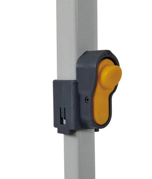A close-up view of a yellow quick-release height adjustment button on the grey metal leg of an OZtrail gazebo.