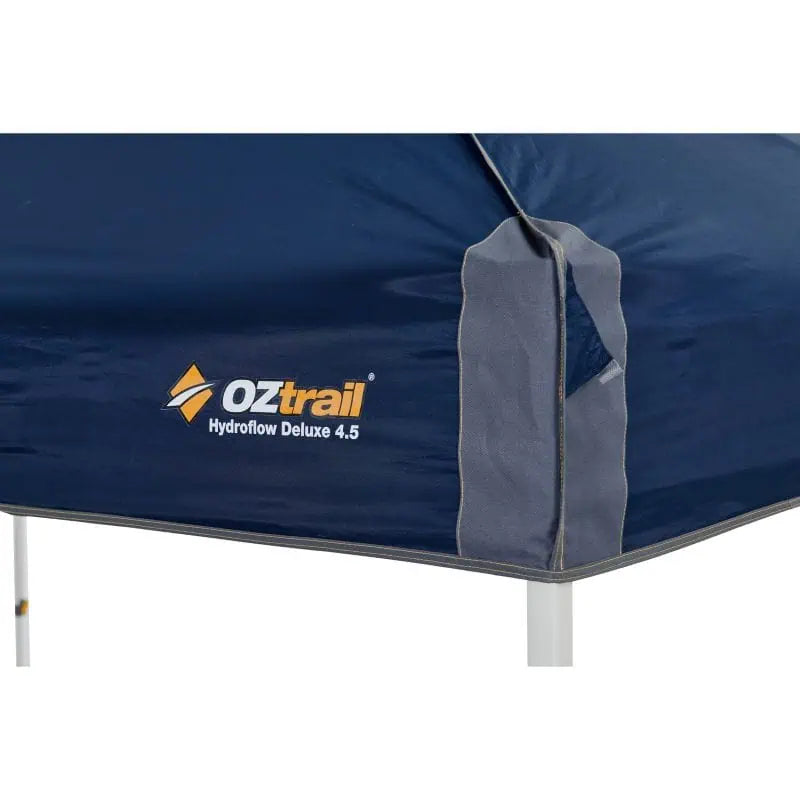 Close-up of the OZtrail Hydroflow Deluxe 4.5 branding and logo on the corner of the navy blue gazebo canopy