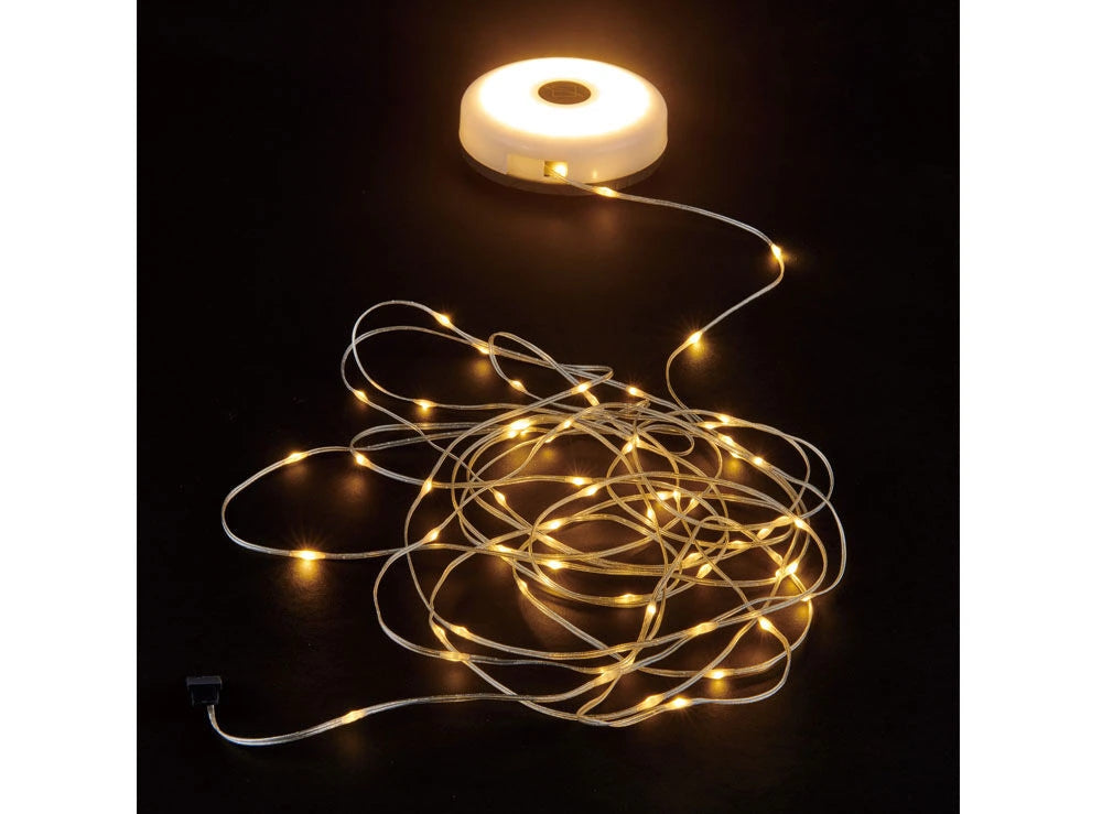 The OZtrail Lumos hub illuminated and connected to a long, tangled string of warm-white LED fairy lights on a black background.