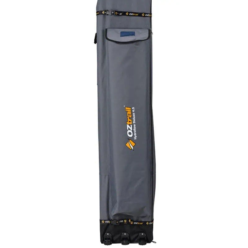 A close-up of the grey OZtrail Hydroflow Deluxe 4.5 storage bag featuring triple wheels at the base and branded straps